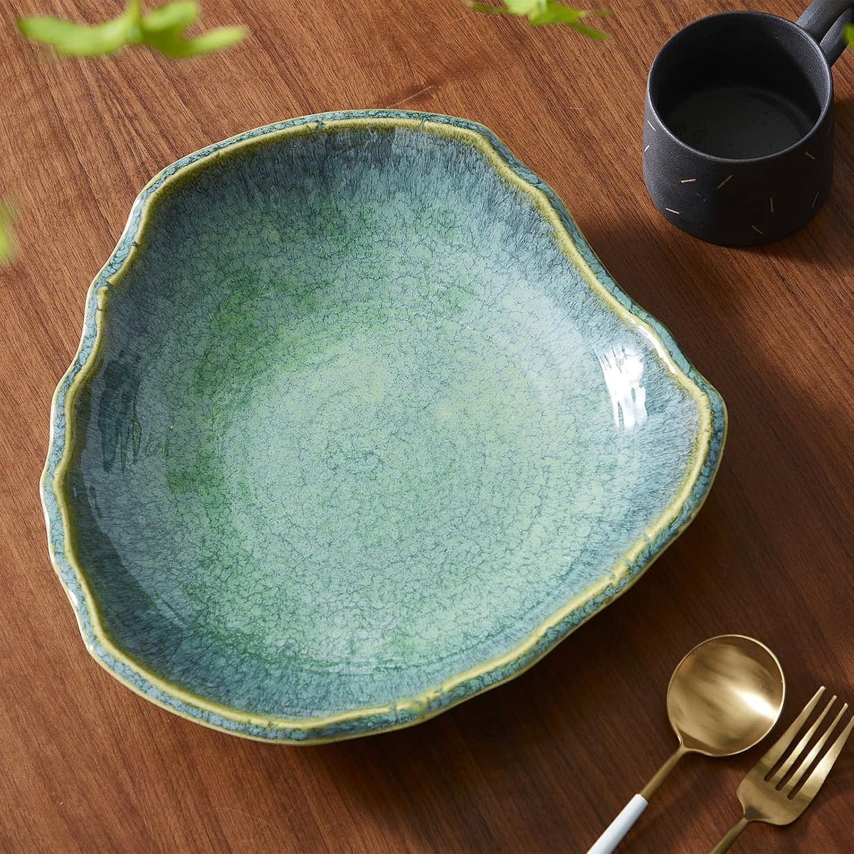Top-down view of emerald green ceramic dish on wood table showing crackled glaze and yellow-rim highlight