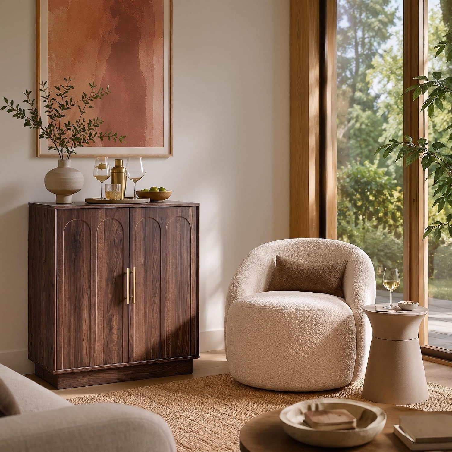 Walnut wine cabinet closed in a sunlit corner beside a rounded cream armchair and tall window.