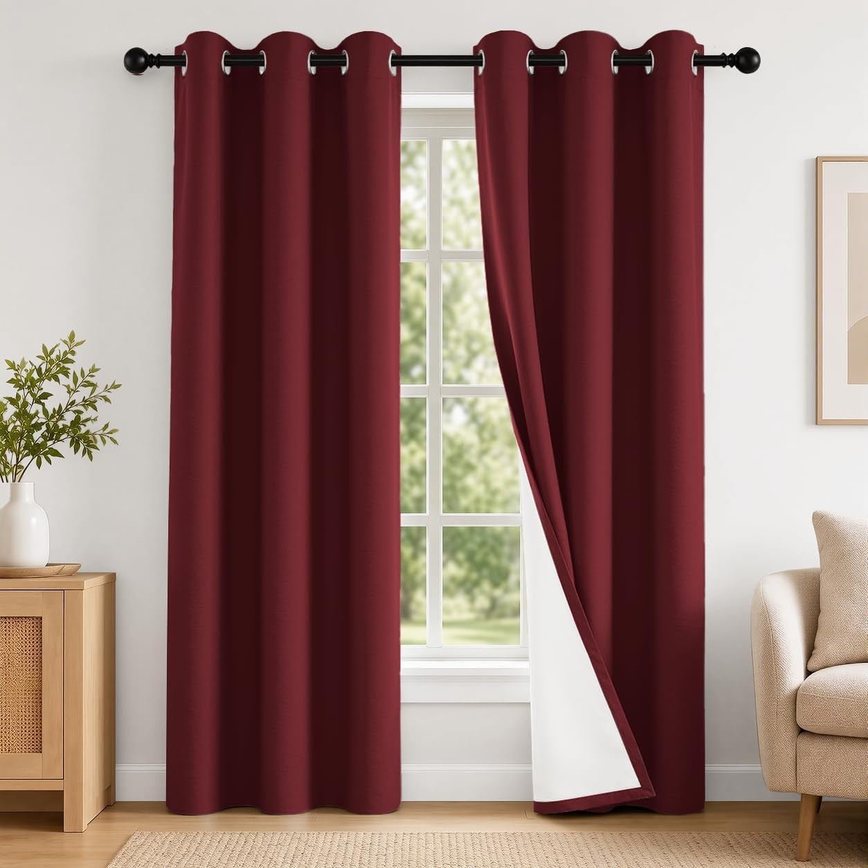 Pair of deep red grommet curtains in a living room setting, right panel folded to reveal white backing