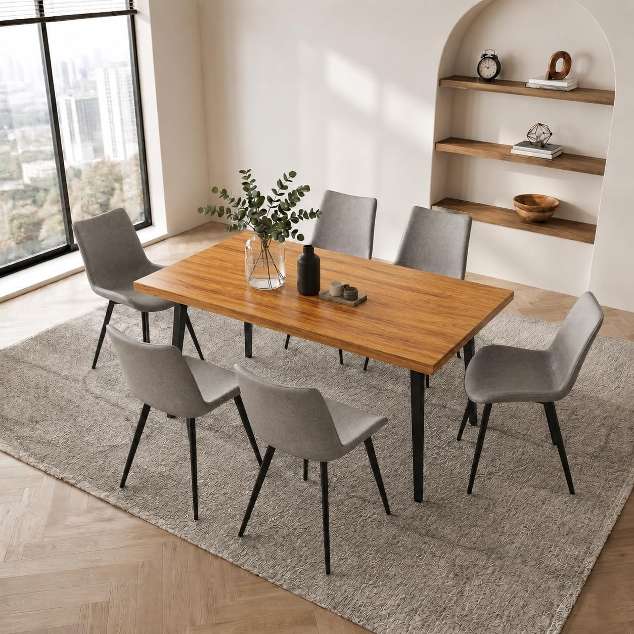 Elevated view of a light wood tabletop surrounded by six light gray upholstered chairs on a patterned rug.