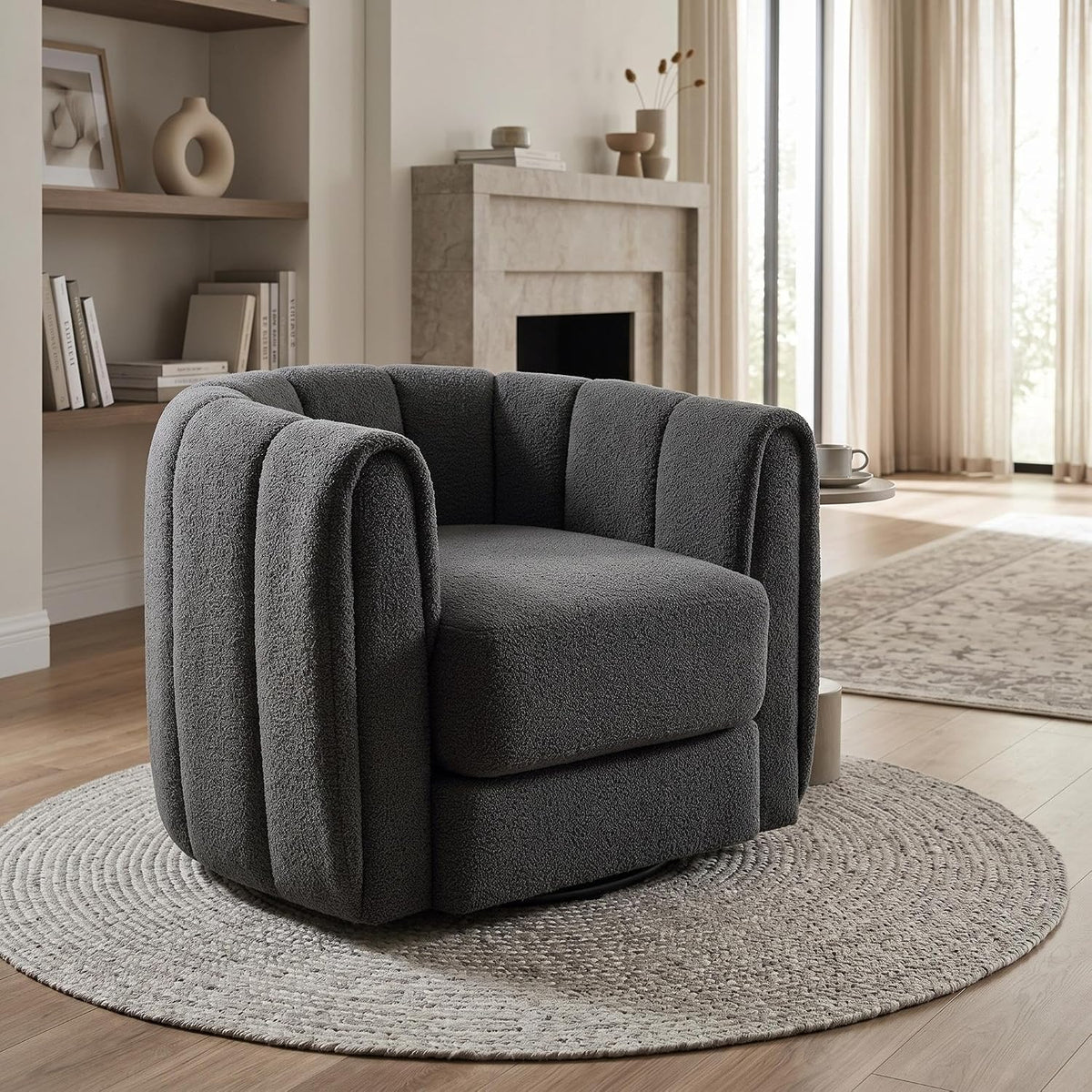 Charcoal-gray swivel barrel chair on a round braided rug with shelves and fireplace in the background.