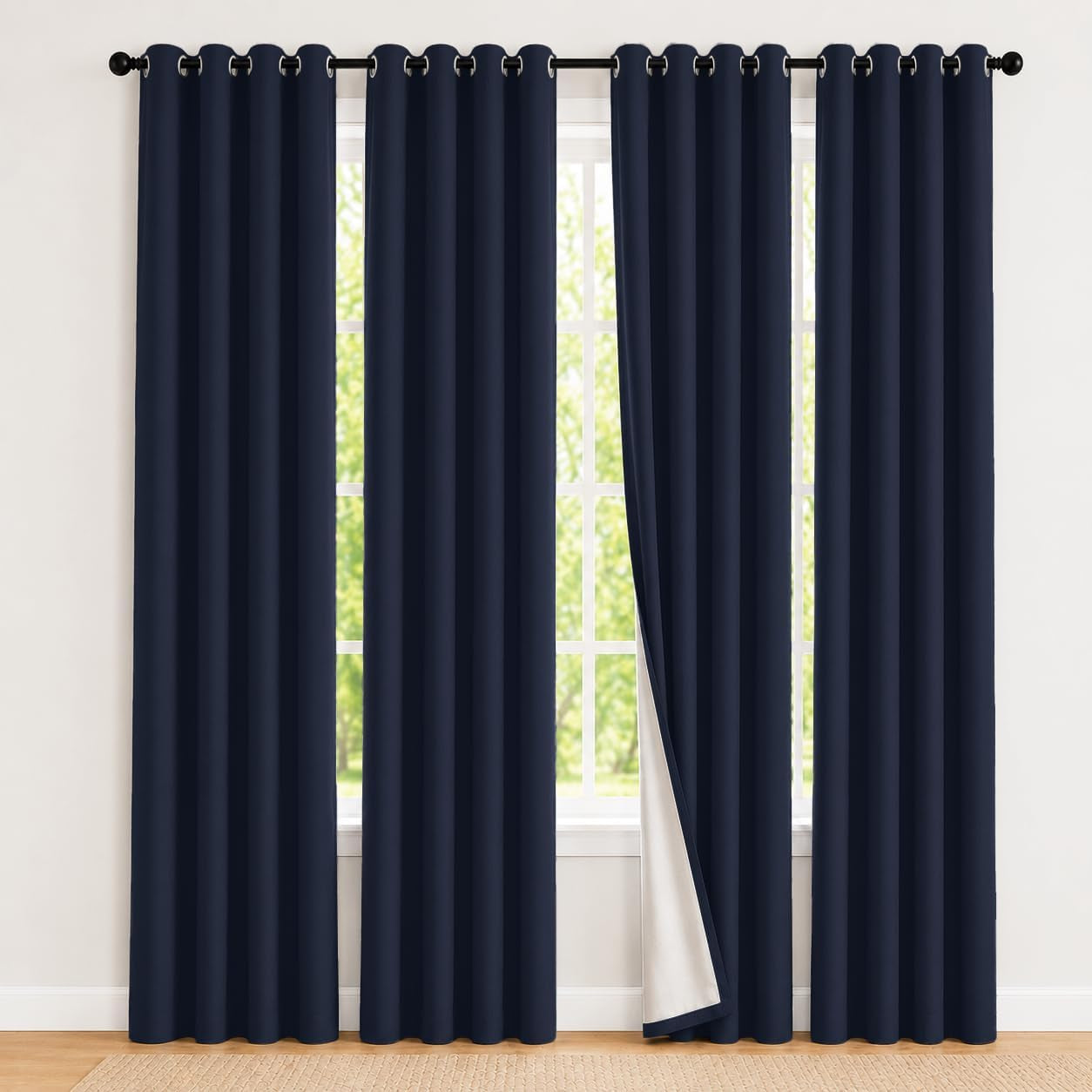 Wide front view of dark blue grommet curtains over a tall window, one panel pulled to show white backing.
