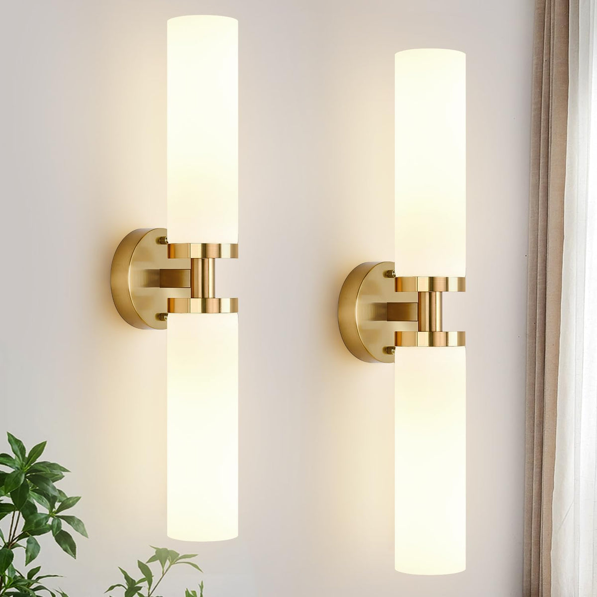 Pair of vertical brushed-gold wall sconces with tall frosted cylindrical shades on a light wall.