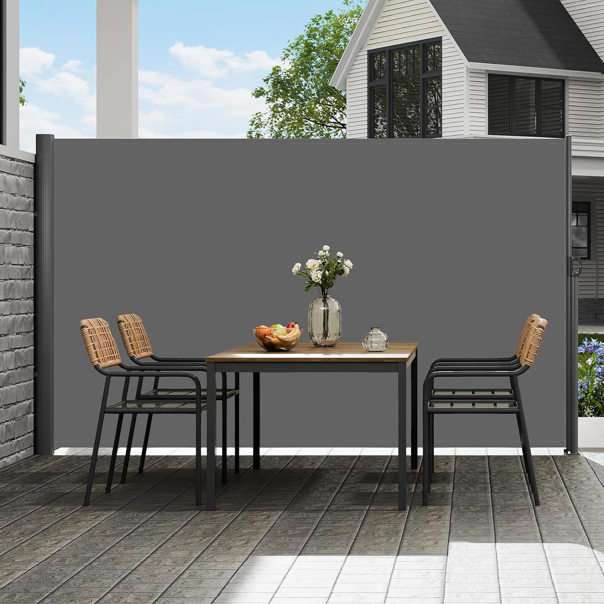 Dark gray retractable side screen extended between posts on a patio with a dining table in front
