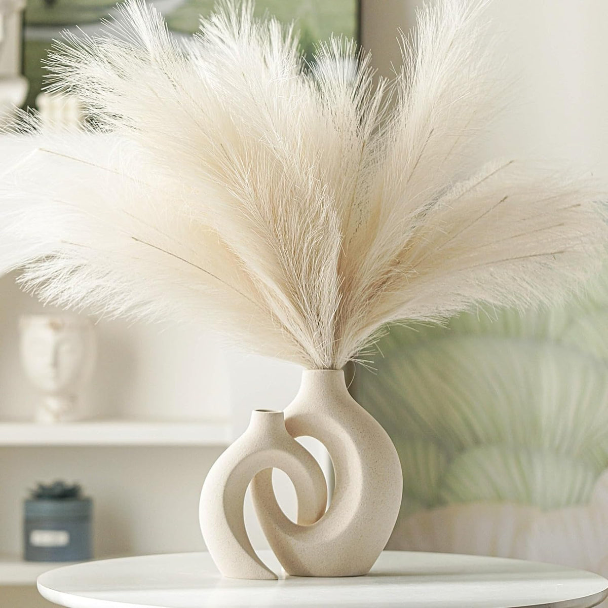 Tall pampas arrangement in the larger matte beige vase shown from front on a white table