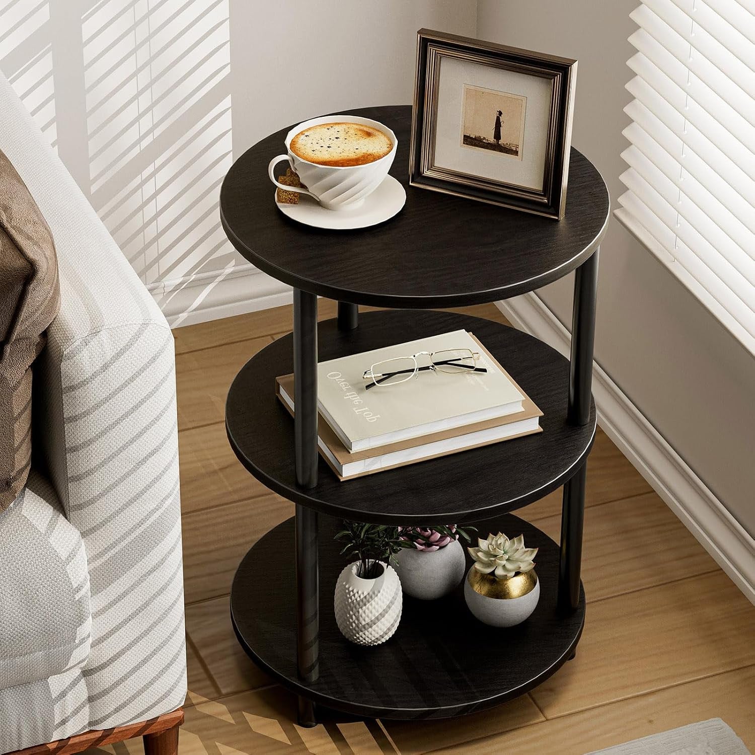 Dark brown three-tier round table next to a sofa topped with a cup and framed photo, plants below.
