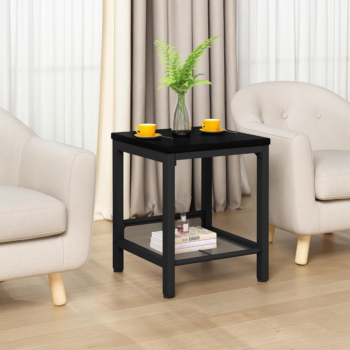 Single black square end table with mesh lower shelf between two beige armchairs.