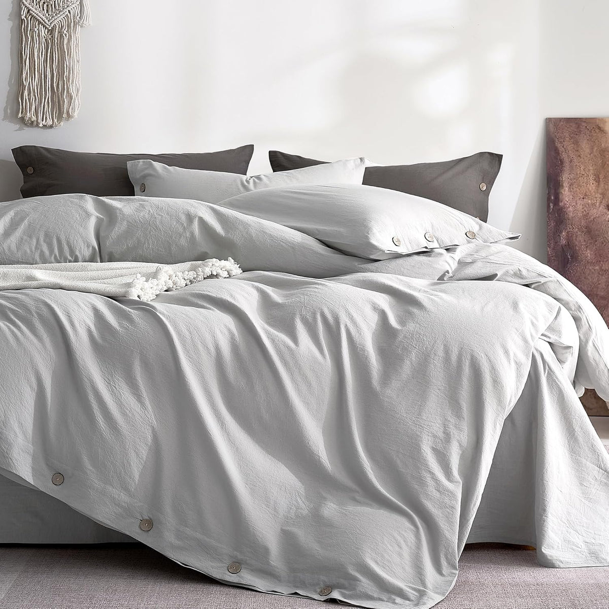 Close-up of pale gray washed-cotton duvet and pillowcases showing wooden button closures along edge