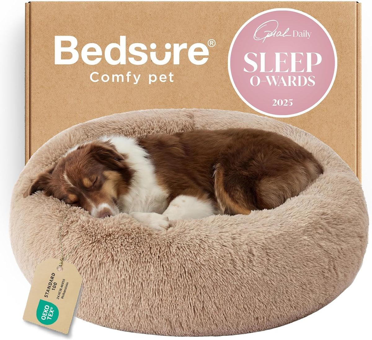 Close-up front view of a tan faux-fur donut dog bed with a brown dog curled up sleeping against a cardboard box background.