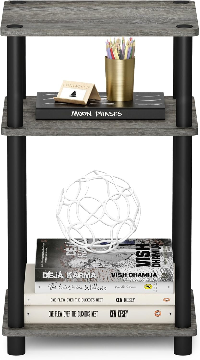 Three-tier end table with gray wood shelves and black cylindrical legs holding books and decor