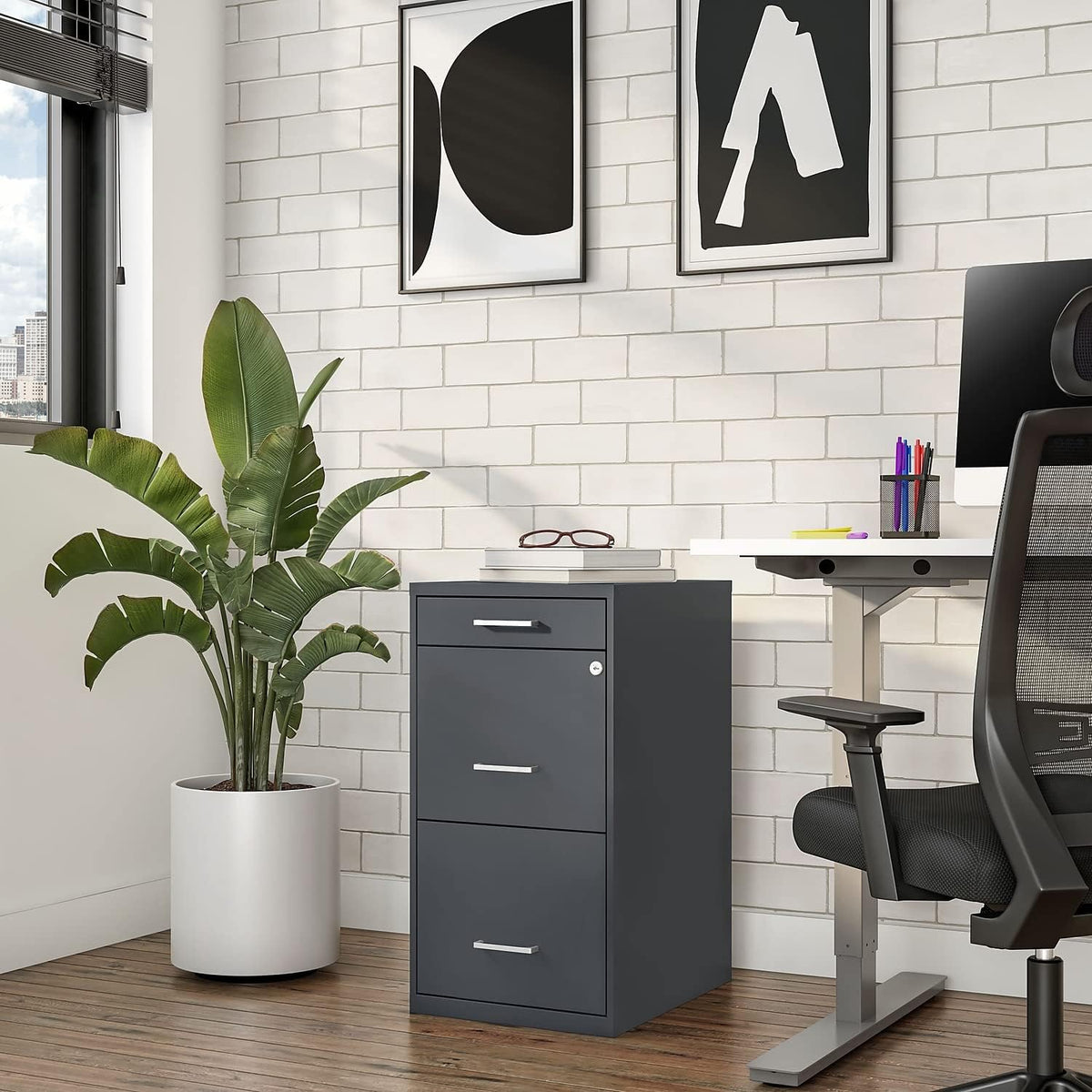 Charcoal three-drawer vertical file cabinet placed beside a desk and plant in a bright home office.