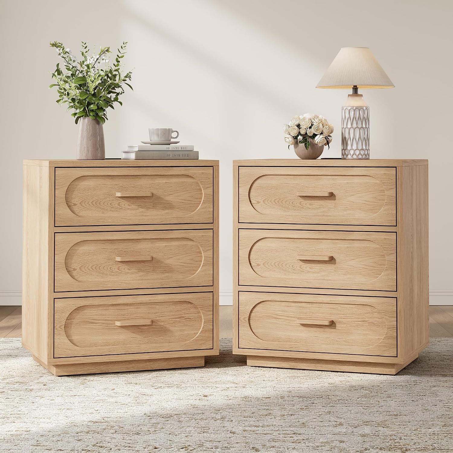 Two matching light-oak three-drawer nightstands side by side with lamps and decor