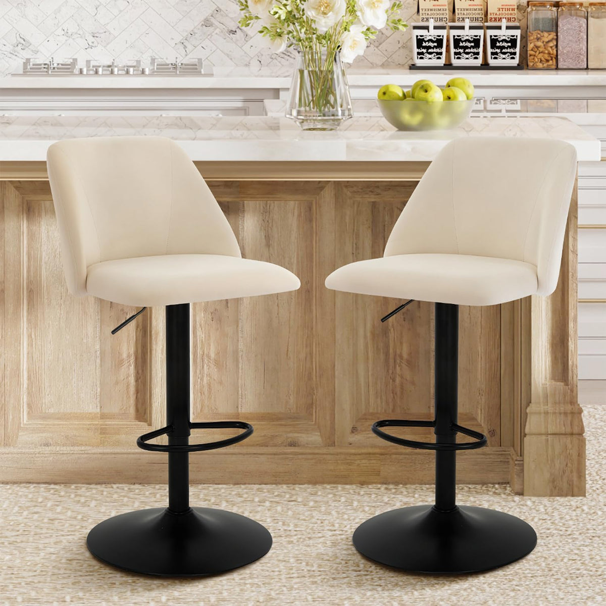 Two beige fabric swivel bar stools front view at a kitchen island with black pedestal bases