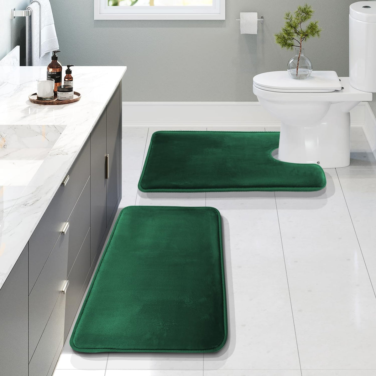 Bathroom scene with three rich green memory-foam rugs: rectangular runner in foreground, second rectangle, and a U-shaped