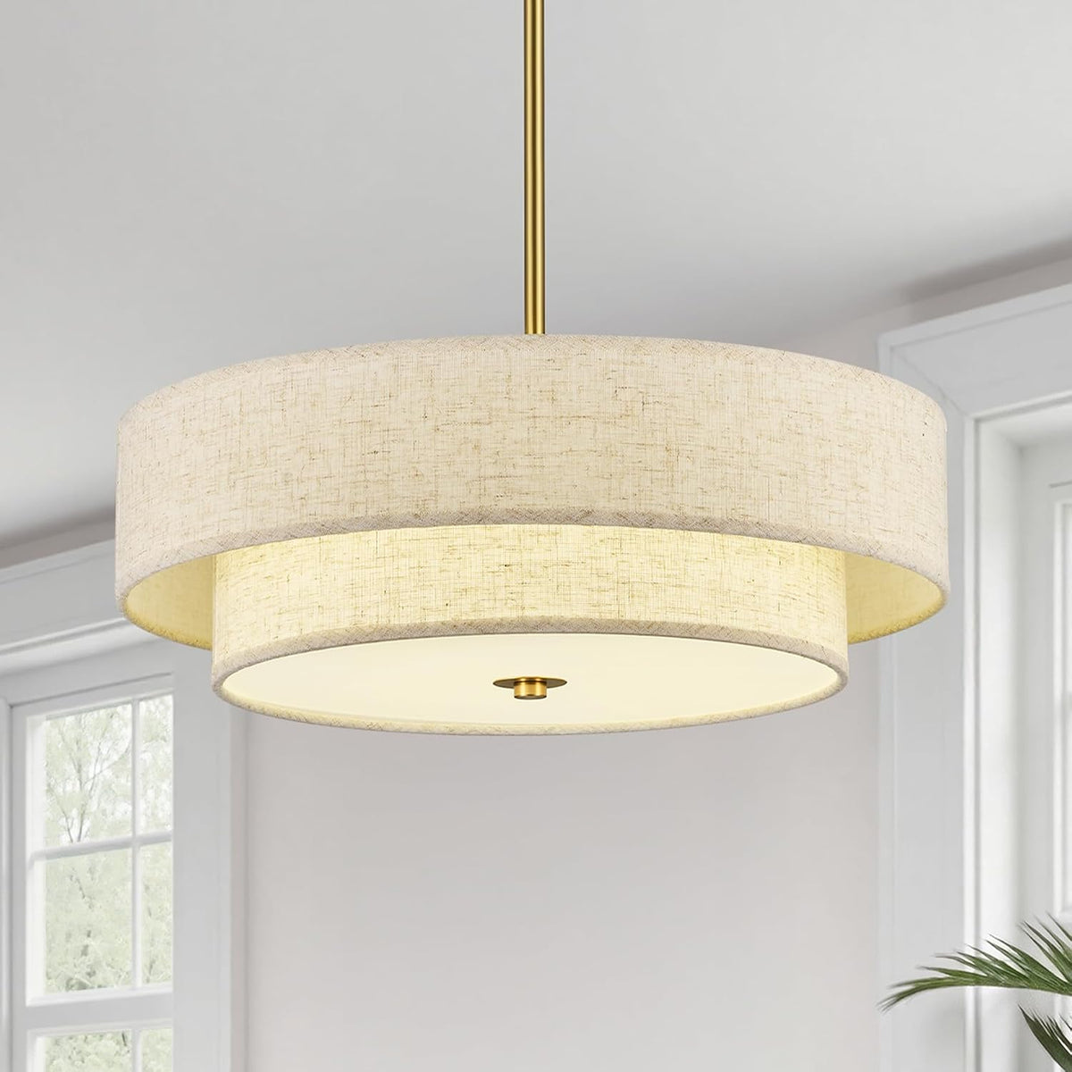 Two-tier beige linen drum chandelier close-up showing fabric shade and gold downrod