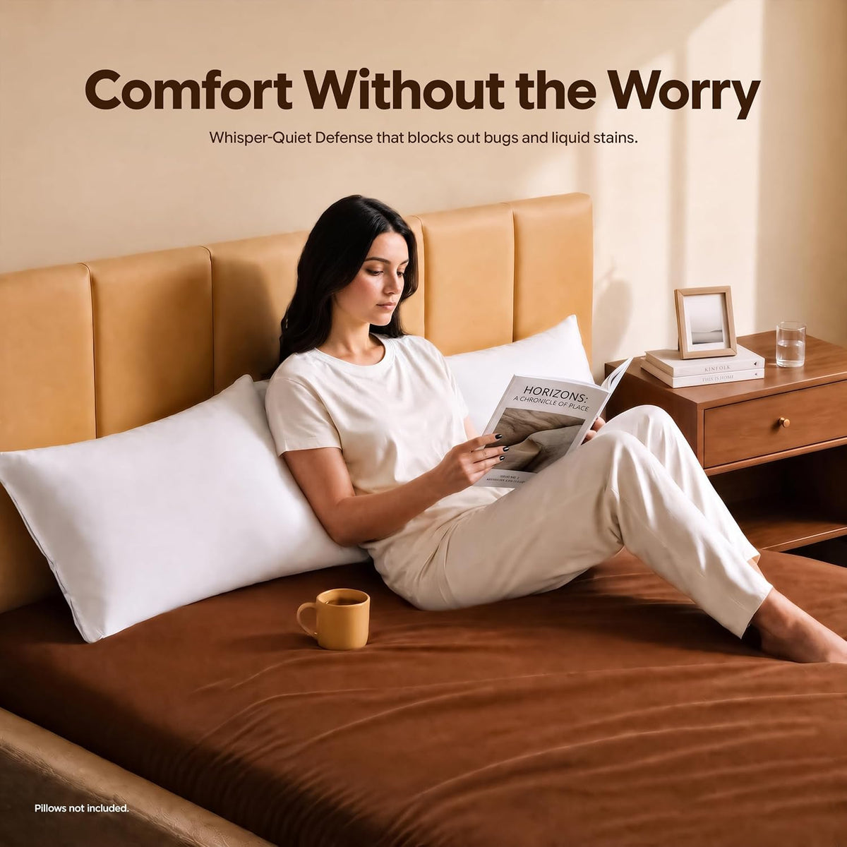 Woman sitting on a bed reading a book with a white zippered pillow cover propped behind her and a mug on the mattress.