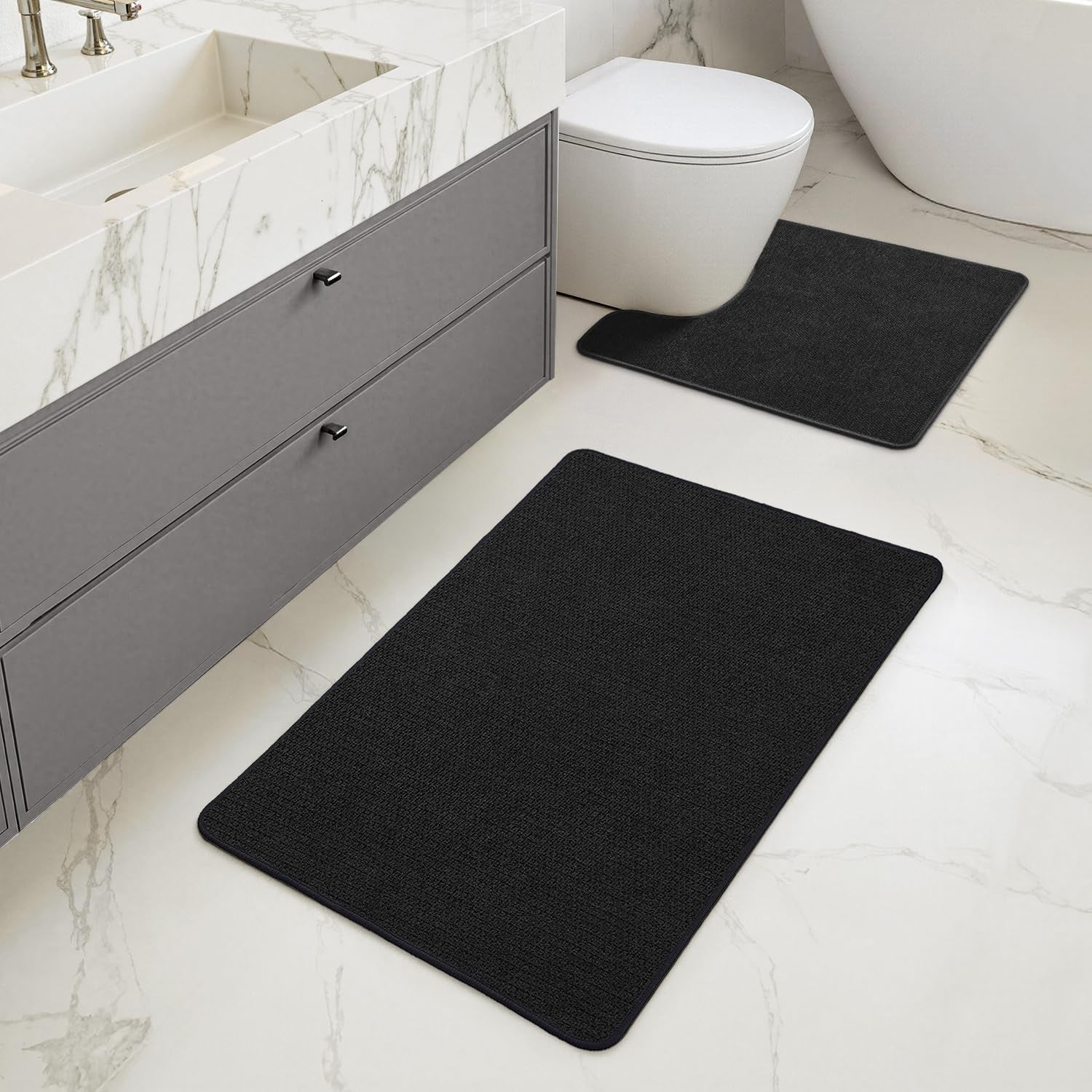 Bathroom vanity and toilet with two black rugs, one rectangular runner and one U-shaped mat at the toilet