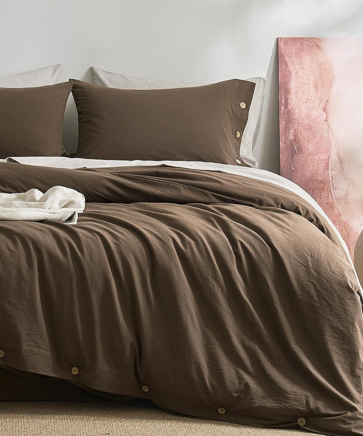 Close-up of a bed dressed in dark brown duvet cover and matching pillowcases with wooden buttons.