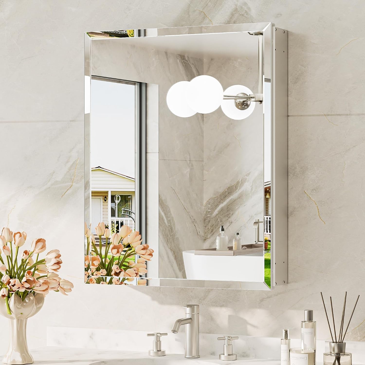 Front view of a recessed beveled mirror cabinet reflecting a round triple-bulb wall sconce and tub.