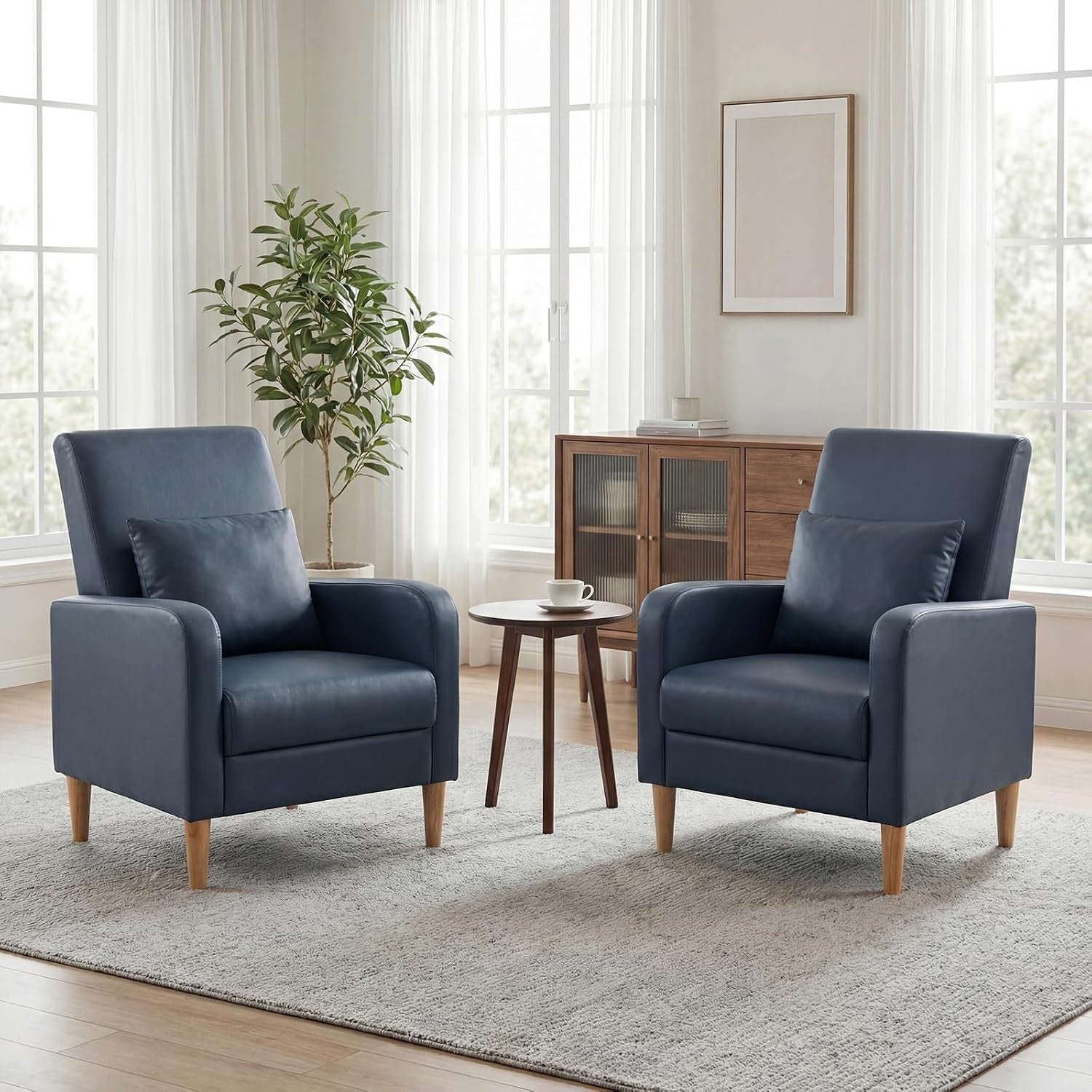 Pair of beige-tone accent chairs with wooden legs arranged around a small round side table in a bright living room