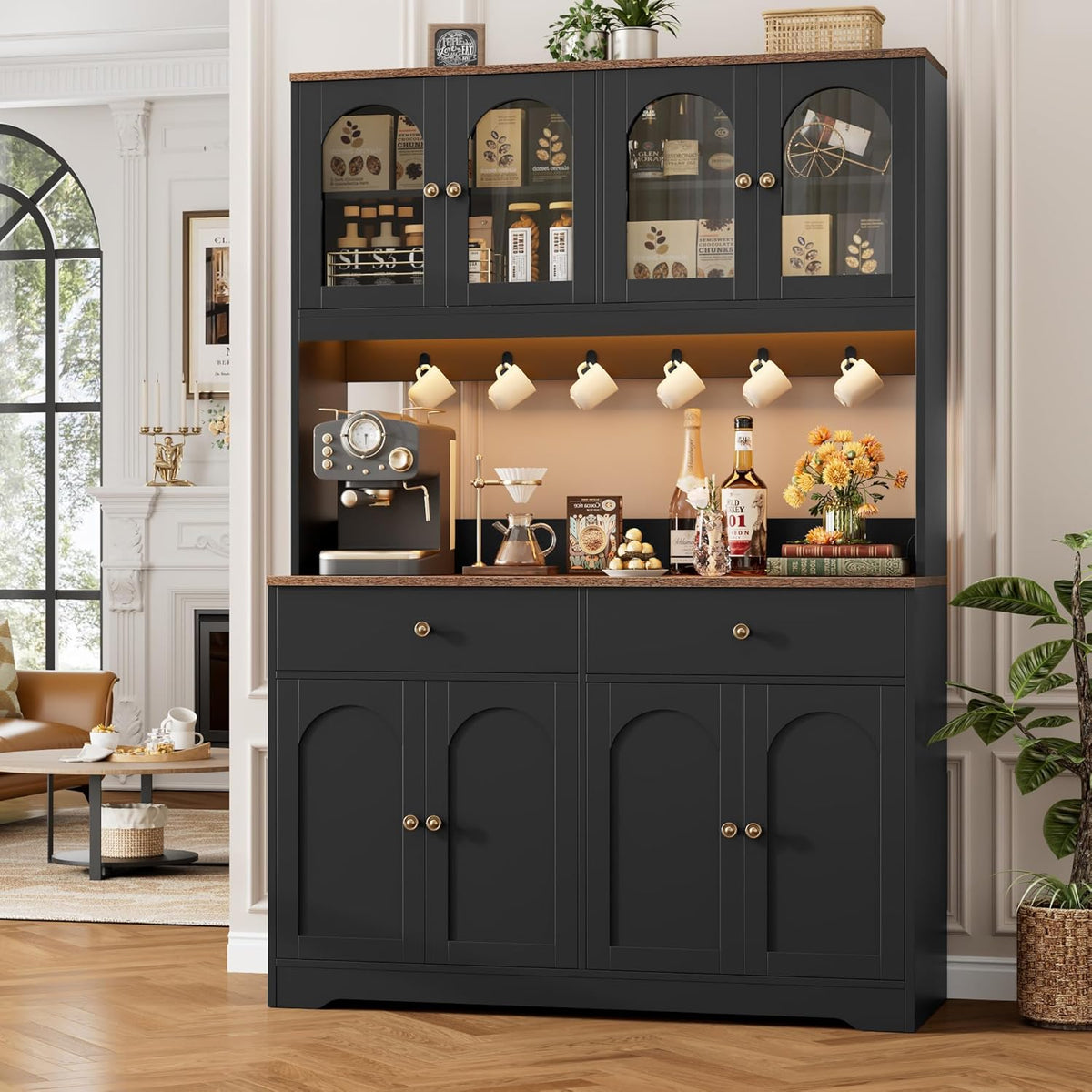 Black pantry hutch shown in a living area with a fireplace, coffee station and hanging mugs