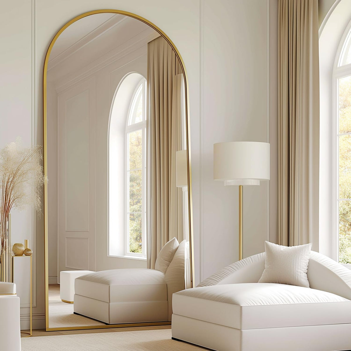 Gold-framed arched mirror reflecting a plush chaise and floor lamp in a neutral living space.