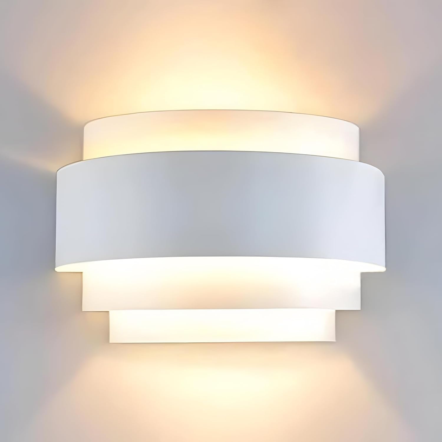 White painted metal half-moon wall sconce front view showing layered semicircular design illuminated