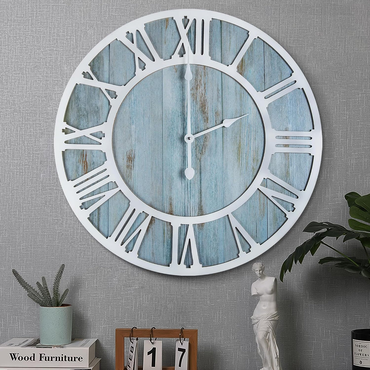Close crop of a different white-framed clock with bluewashed wood dial and Roman numerals on textured wall