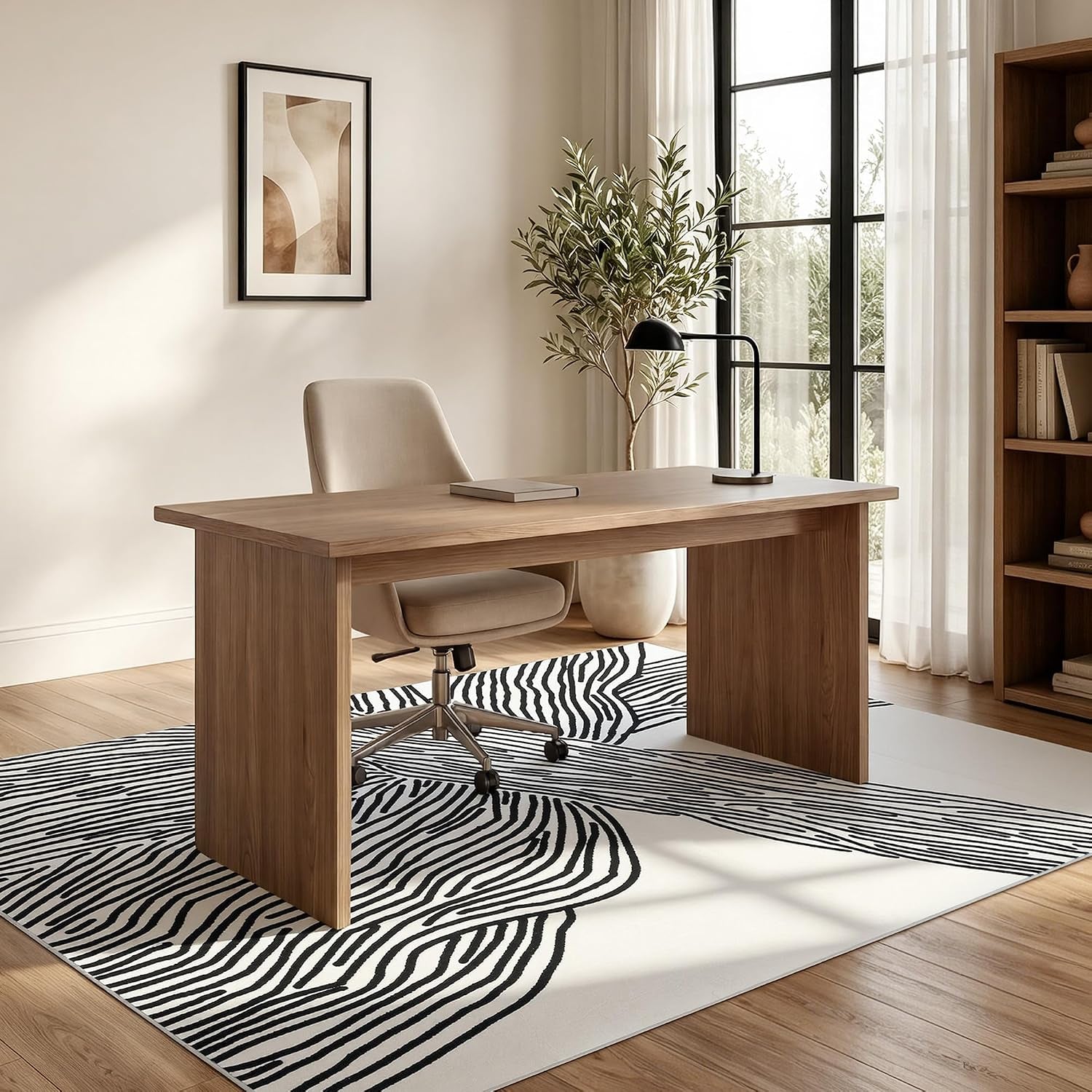 Black and white abstract area rug under a wooden desk and swivel chair, home office scene with natural light