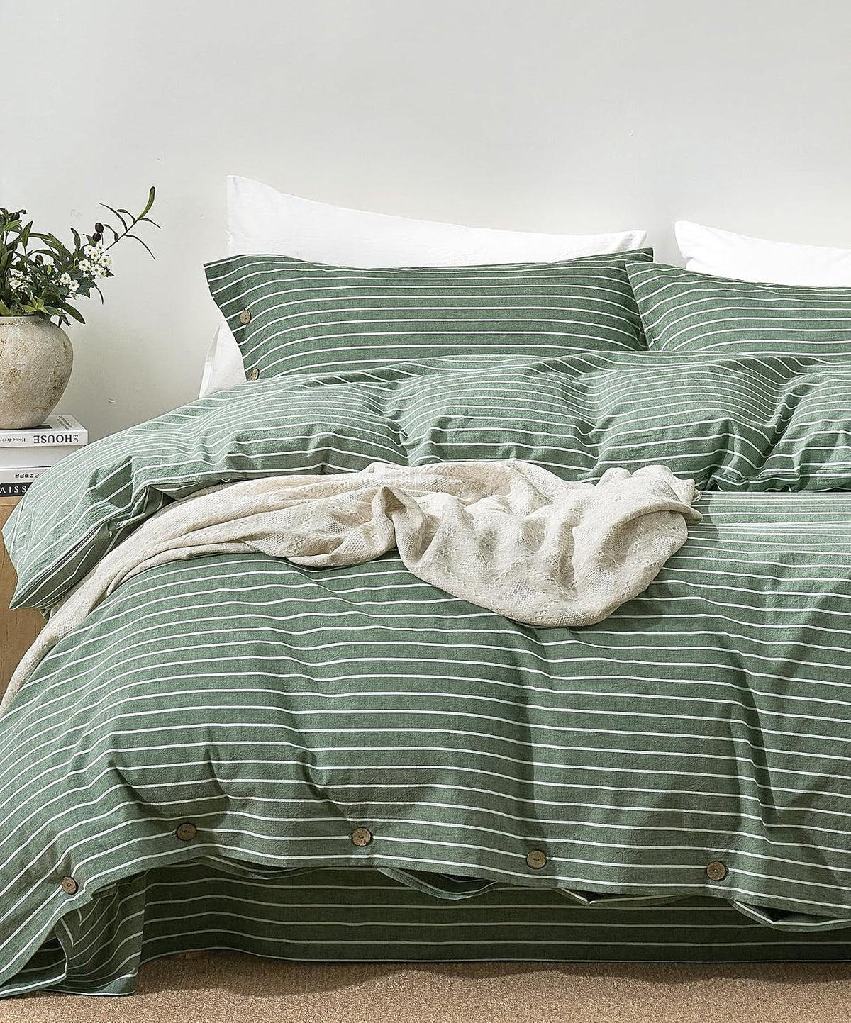 Front view of a bed dressed in green-and-white striped duvet and matching pillowcases with wooden buttons