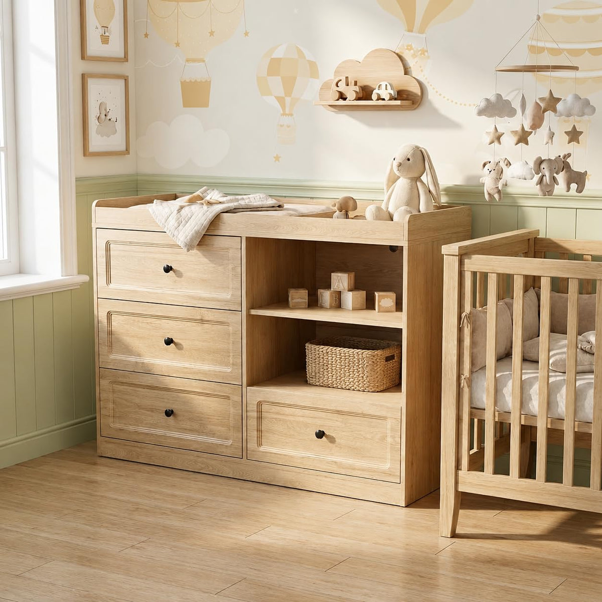 Angled view of natural wood changer with stuffed bunny on top and crib beside it