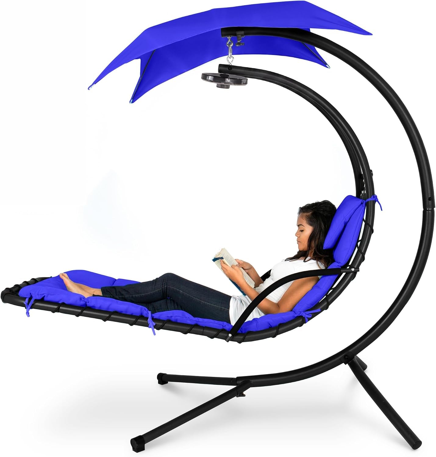 Side view of a curved hanging chaise with bright blue cushions, canopy and a woman reclining reading.