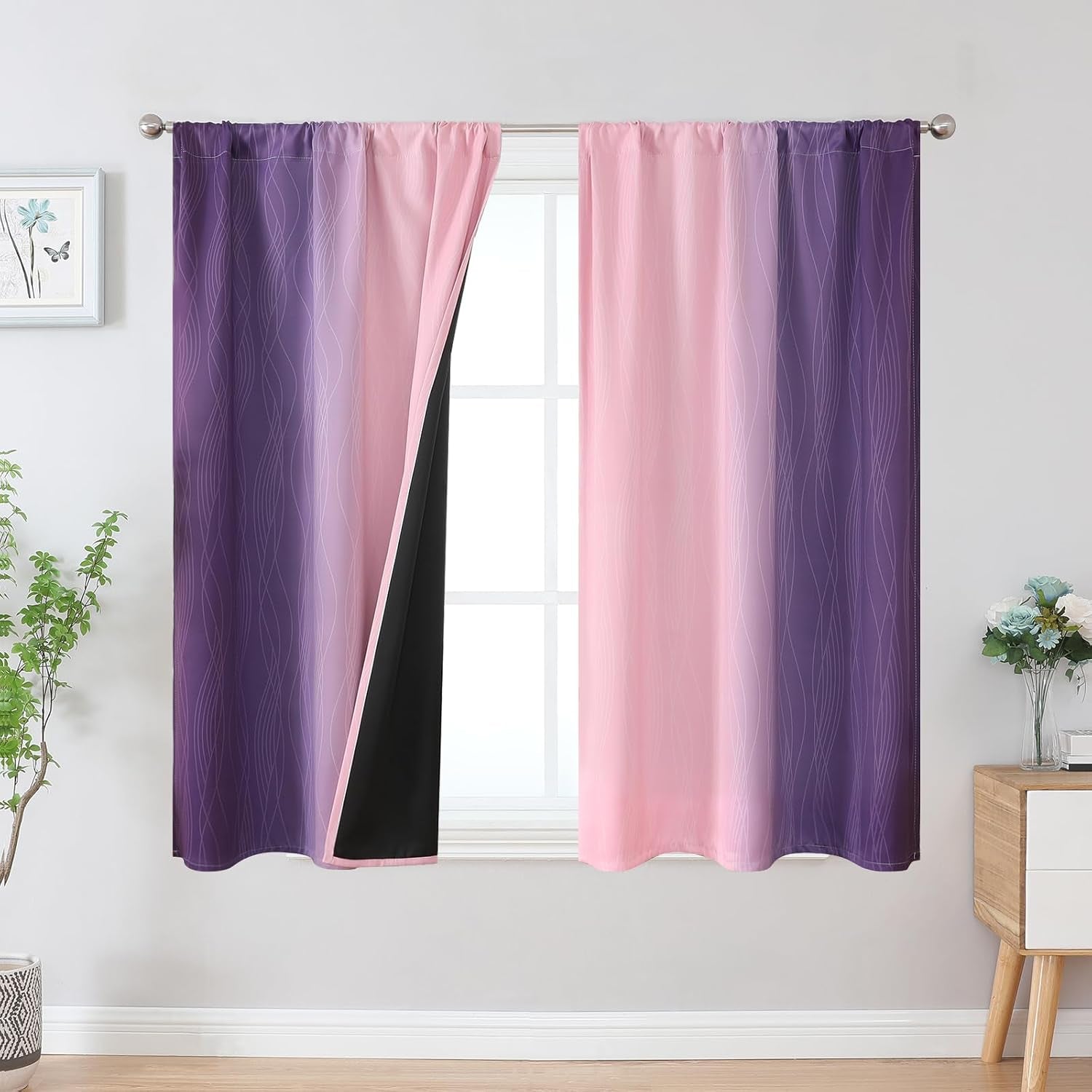 Window with pink-to-purple ombre curtains on a rod, one panel turned to reveal black backing.