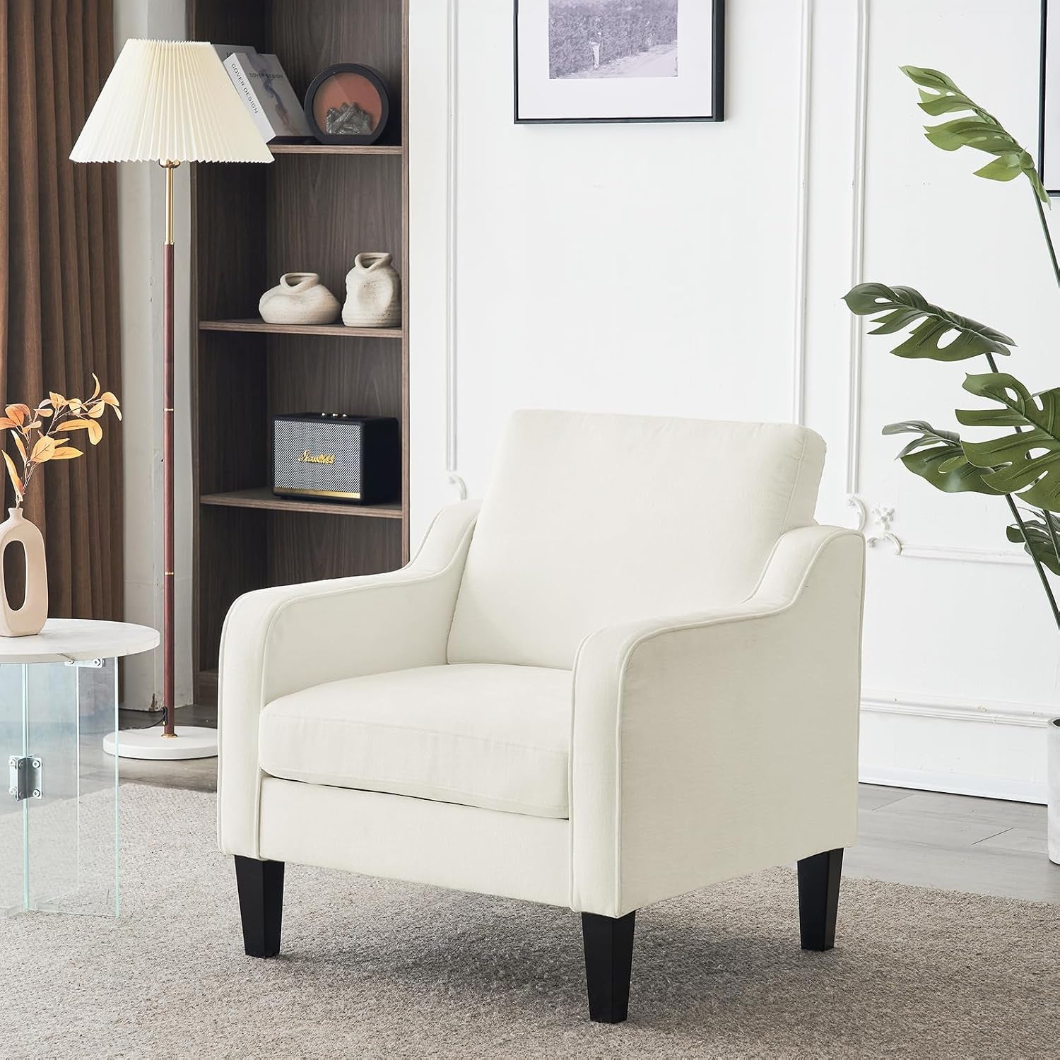 Cream upholstered armchair in a living room beside a floor lamp, bookshelf, and plant.