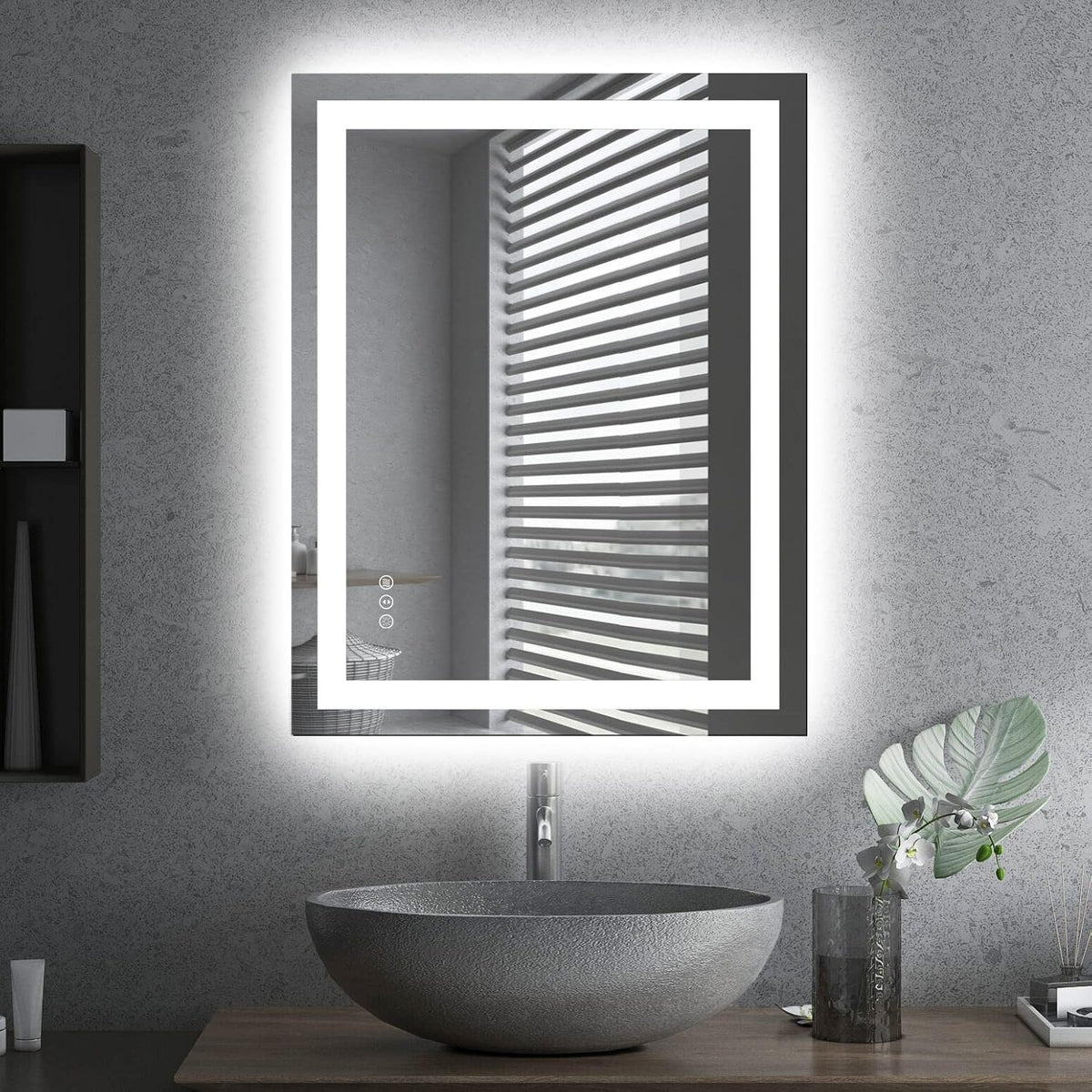 Vertical LED mirror with bright double-frame lighting over a textured stone vessel sink and a small plant on the counter.