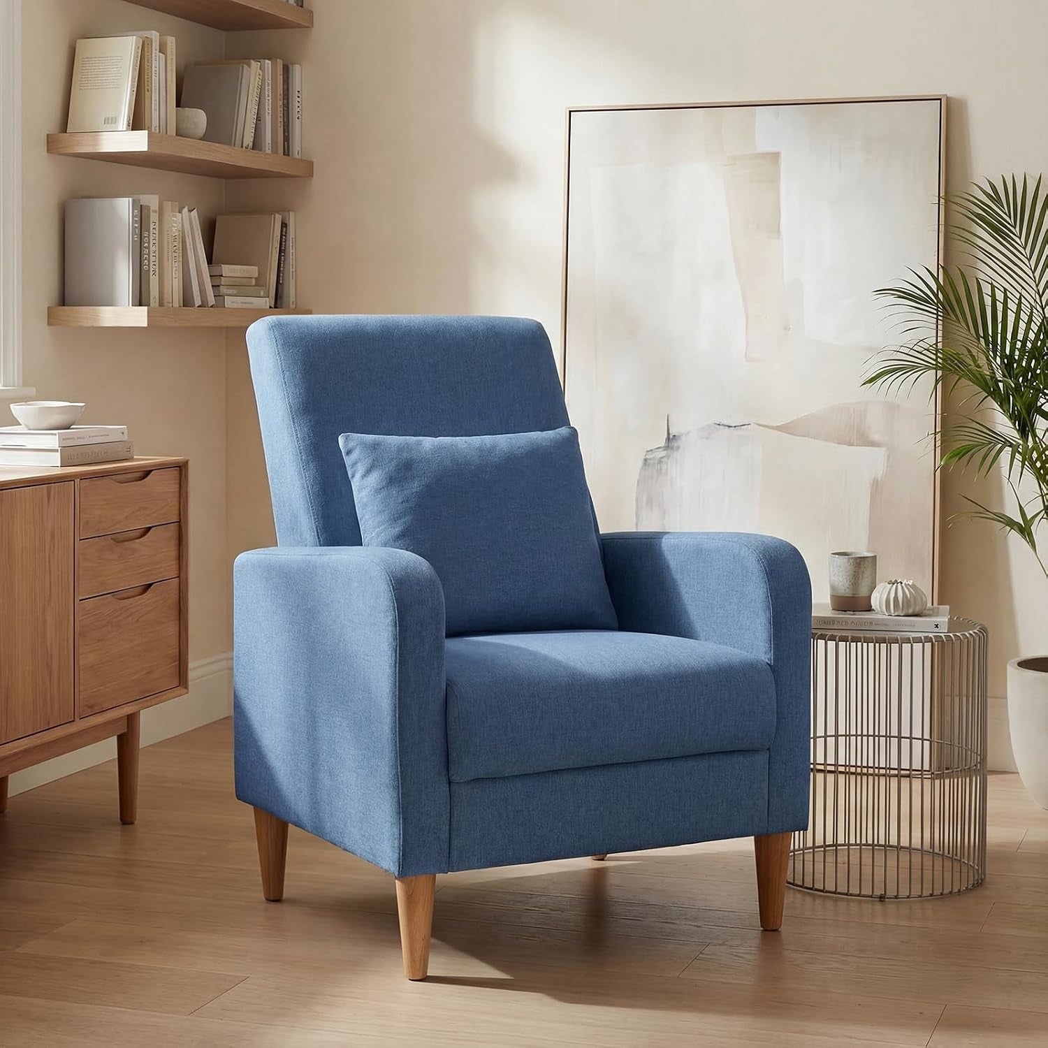 Single blue upholstered accent chair with a square pillow and tapered wood legs in a living room.