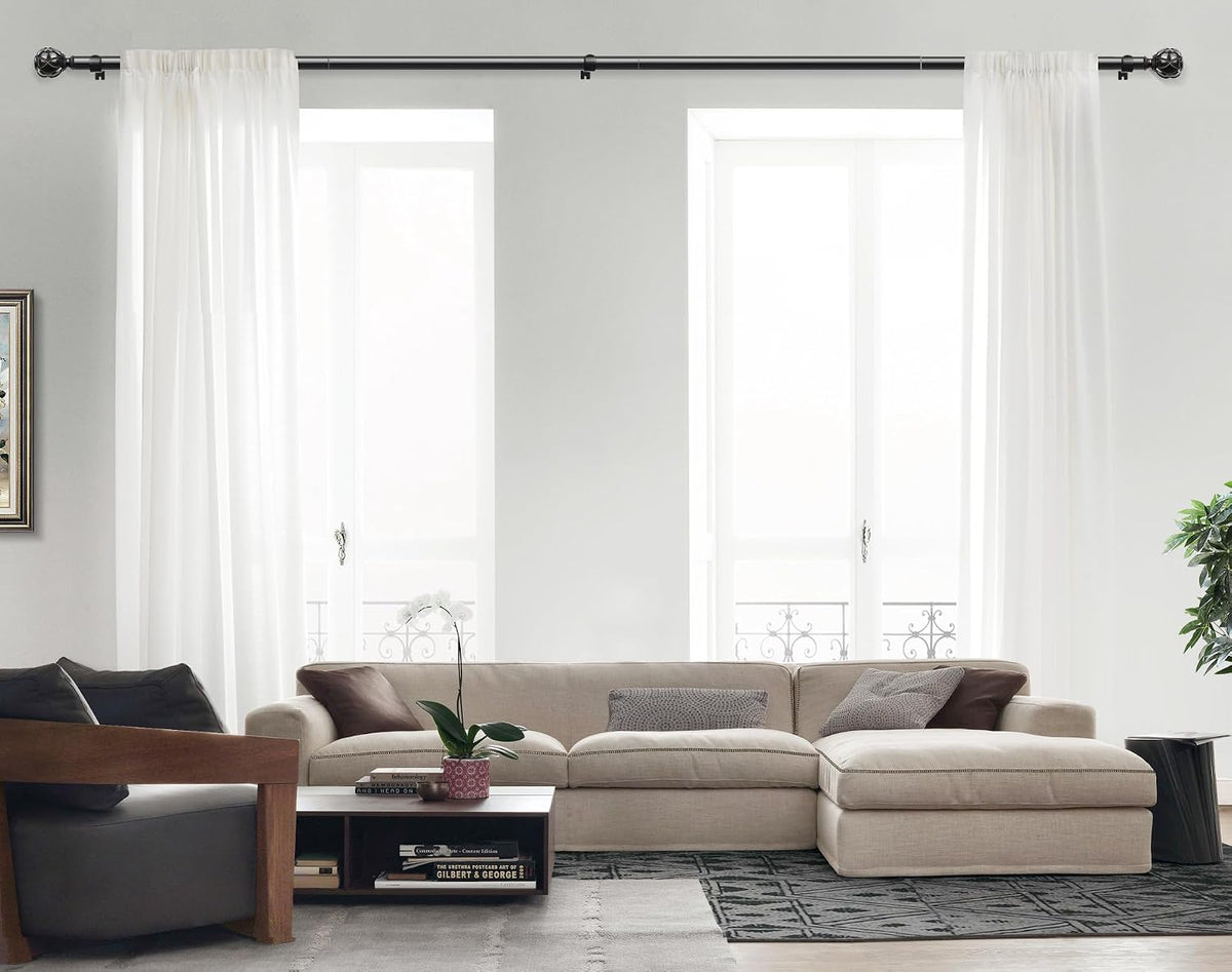 Living room wide shot showing a black curtain rod installed above two tall windows with white sheer panels.