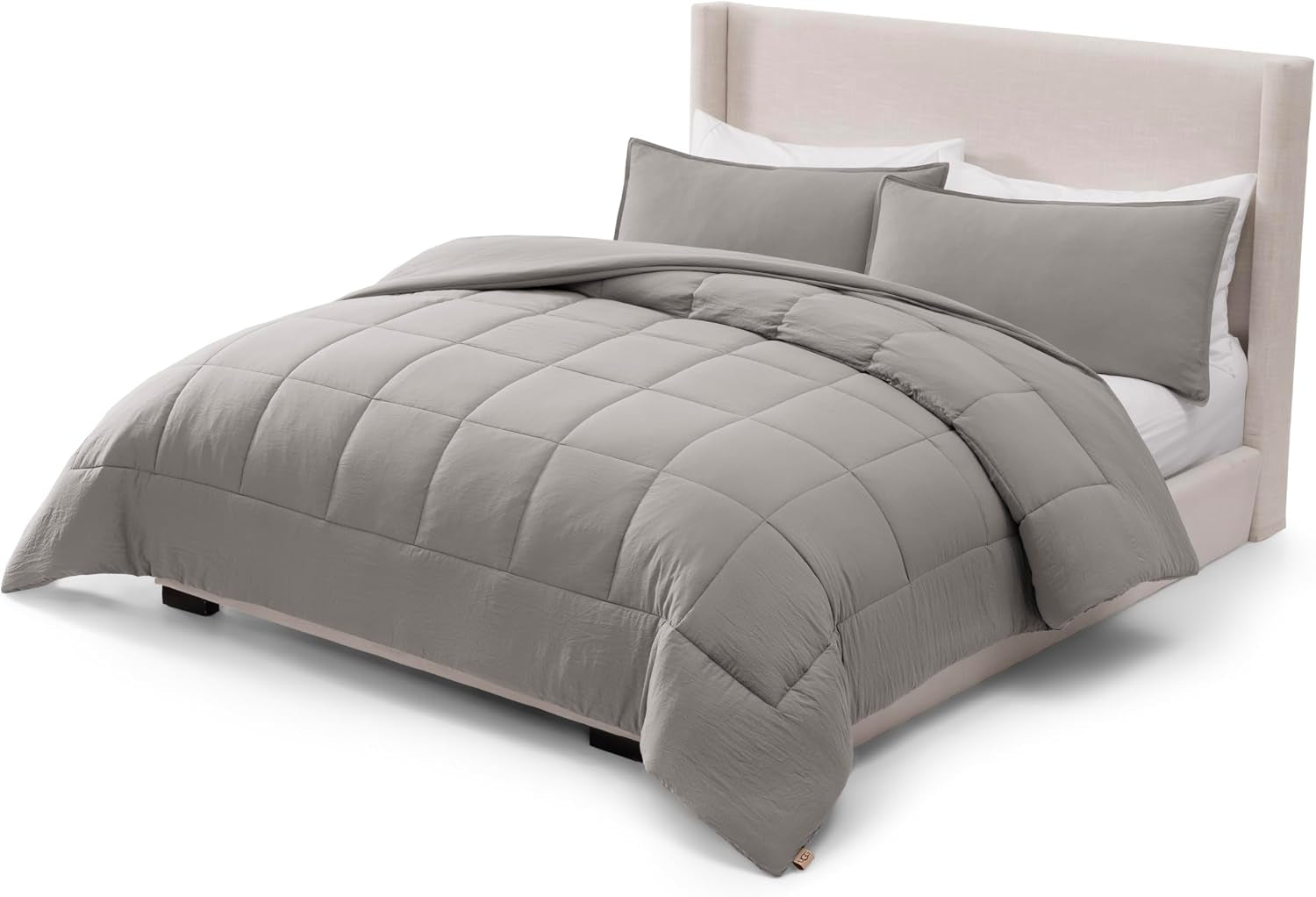 Three-quarter studio view of a made bed with the box‑stitched comforter folded back at the top.