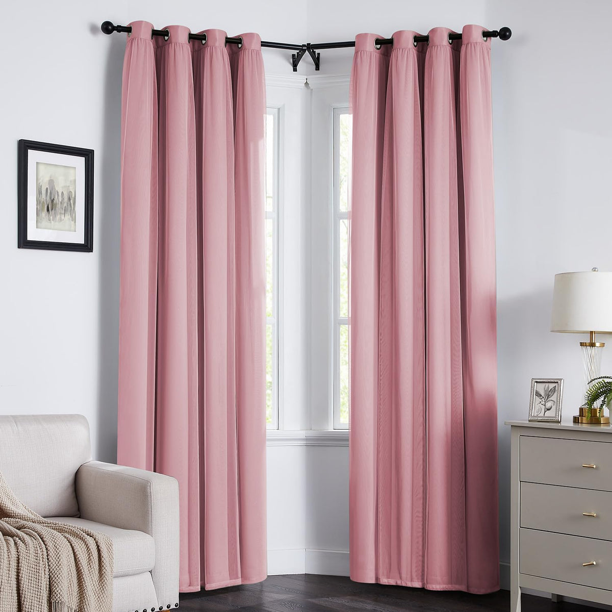Corner living room with pink grommet-top curtains hanging on a black rod framing two tall windows.
