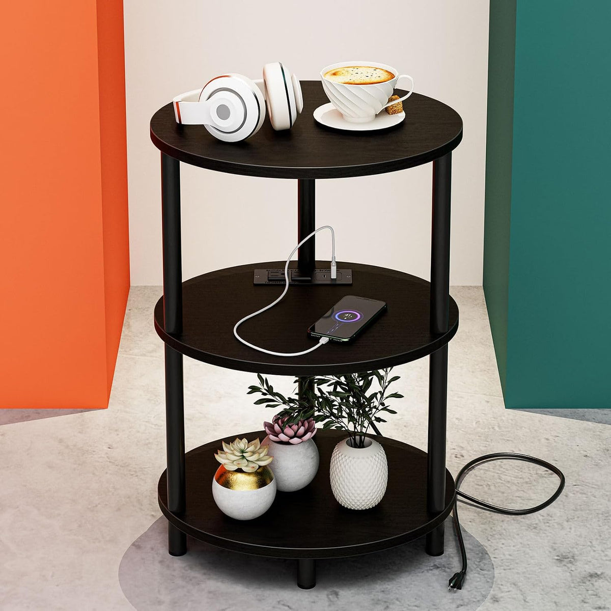 Single dark wood three-tier round table showing a phone charging on the middle shelf and an external power cord on the floor.
