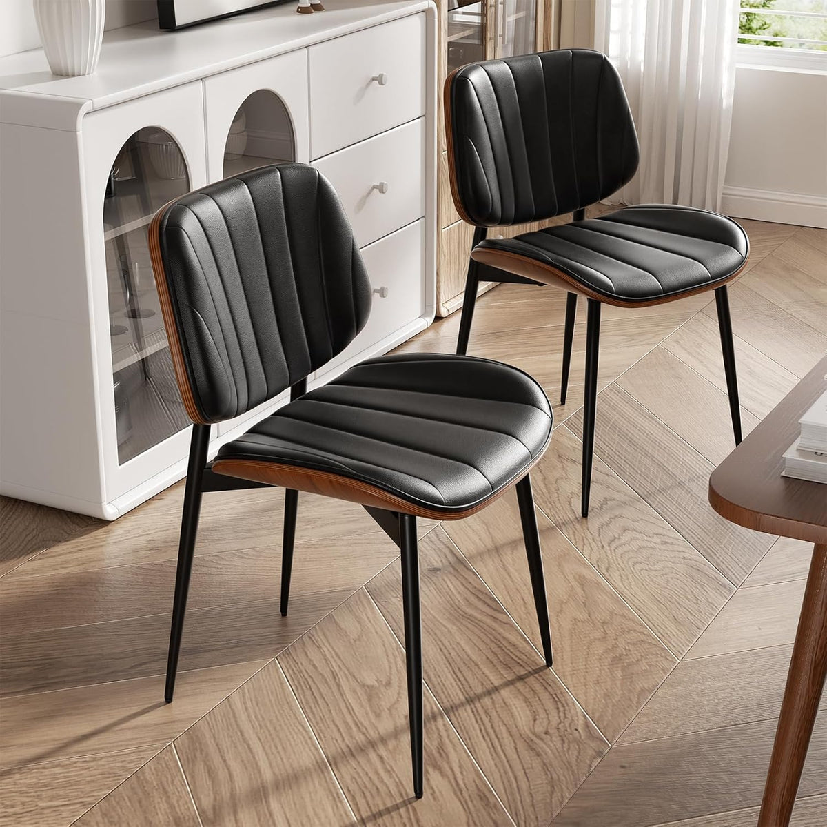 Angled view of two chairs showing tapered black metal legs and curved walnut-finish back and seat edges on wood-look floor.