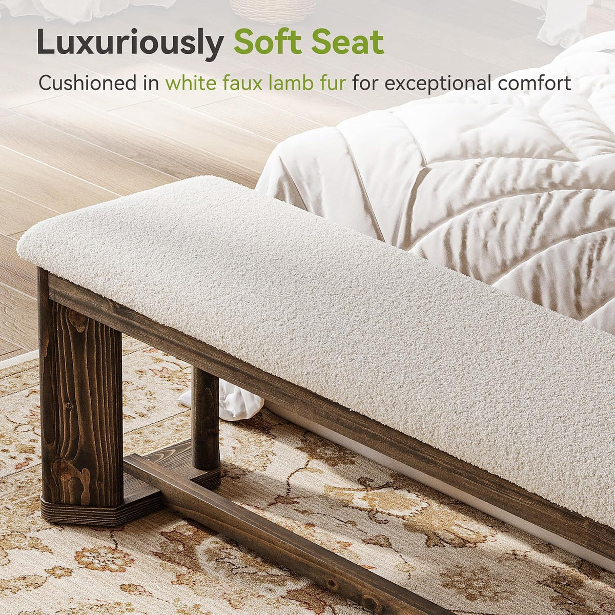 Three-quarter view of the bench beside bedding, highlighting the plush white seat and wood leg joinery on a patterned rug