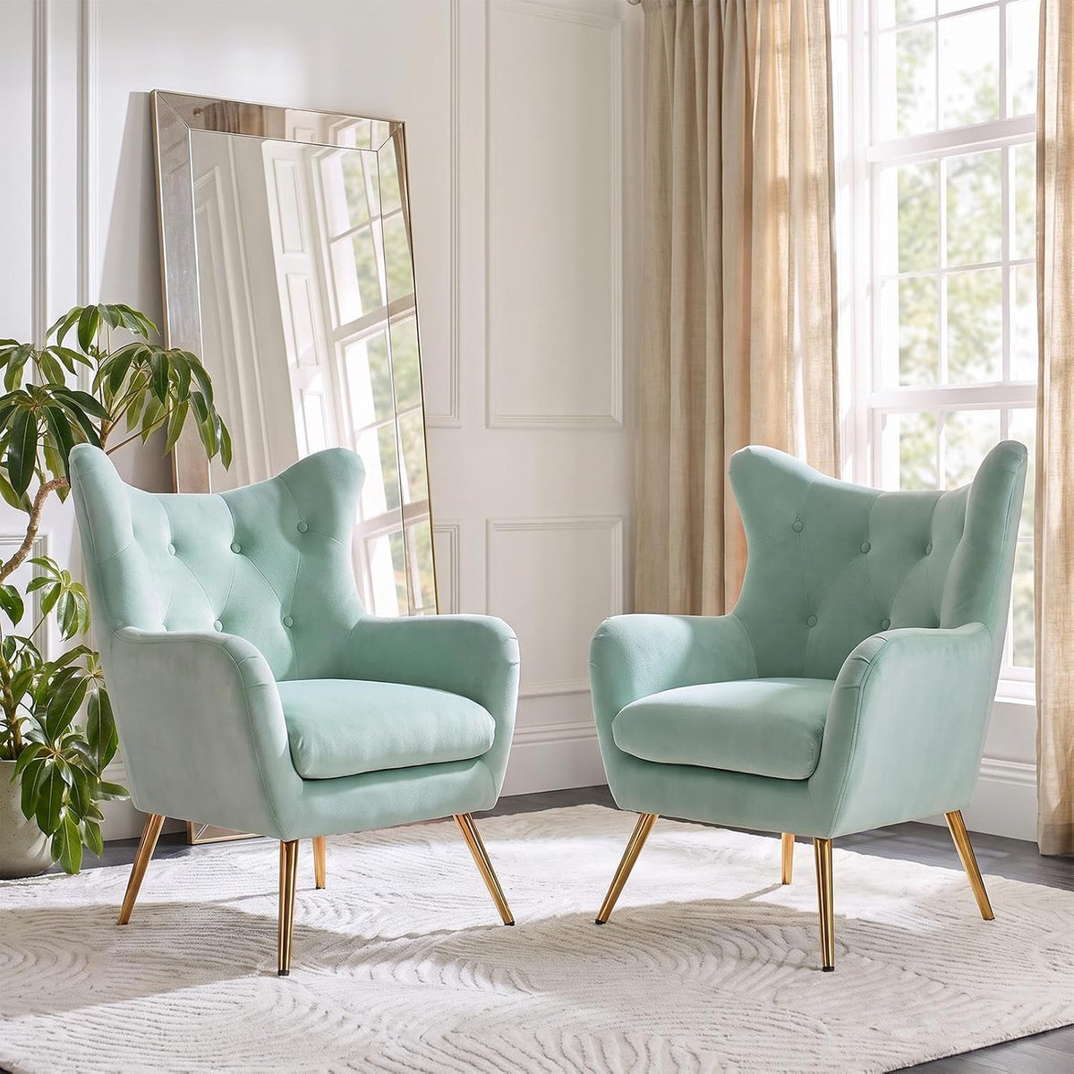 Two mint-green wingback chairs facing forward with a large leaning mirror behind one chair.