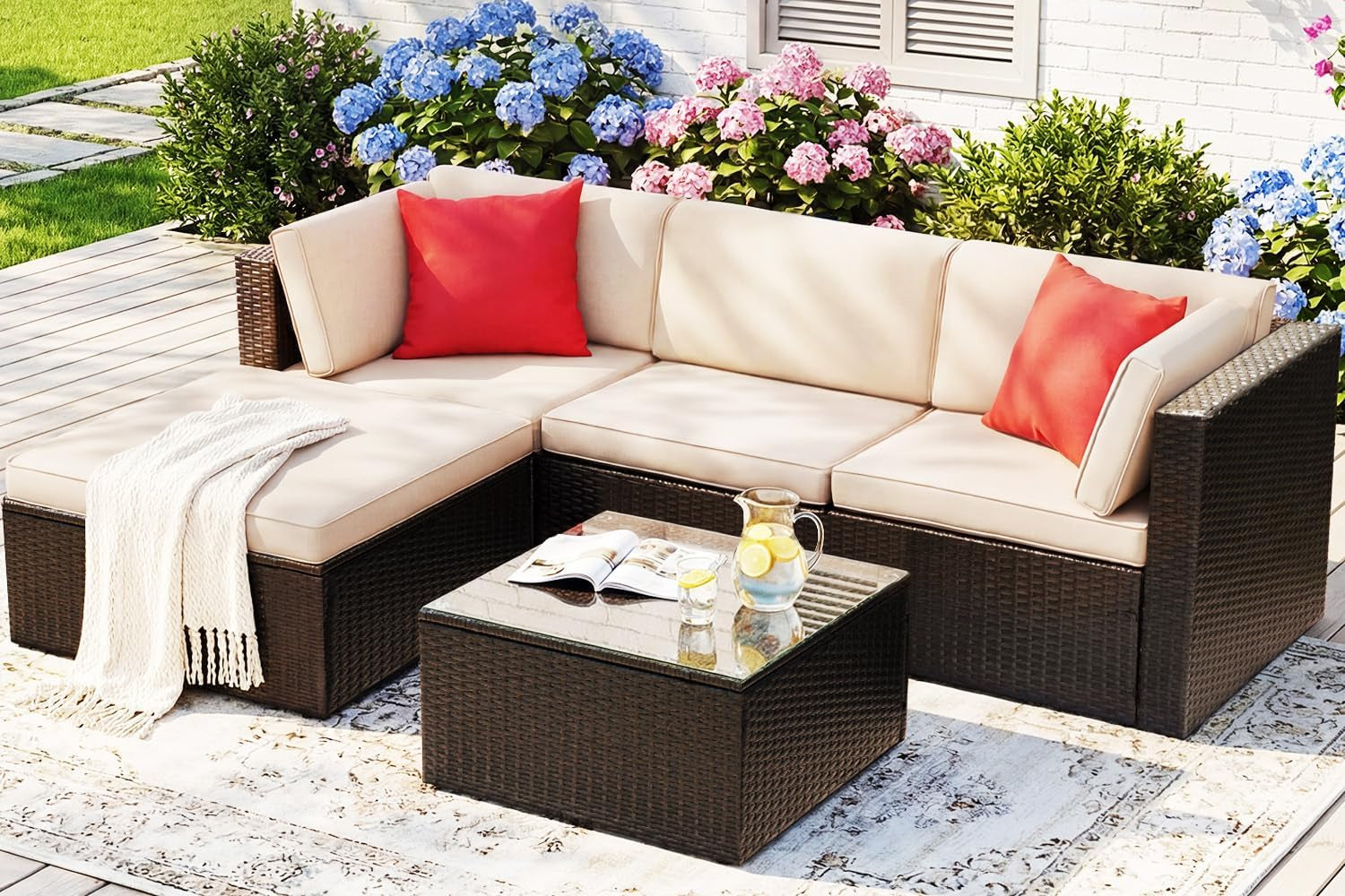Beige-cushioned PE wicker 5-piece outdoor sectional with tempered glass coffee table, angled front view on a deck