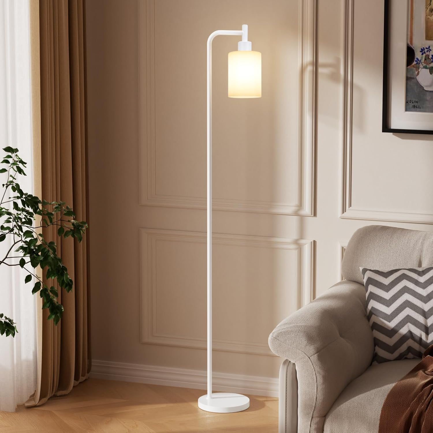 White floor lamp with lit cylindrical shade next to a sofa and drapery in a cozy corner