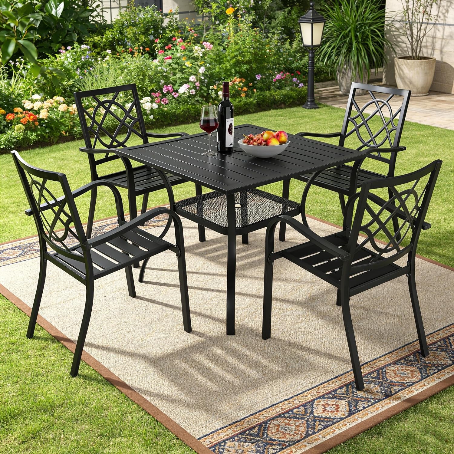 Dining set on a lawn-side rug with floral garden and lamp post visible behind the table