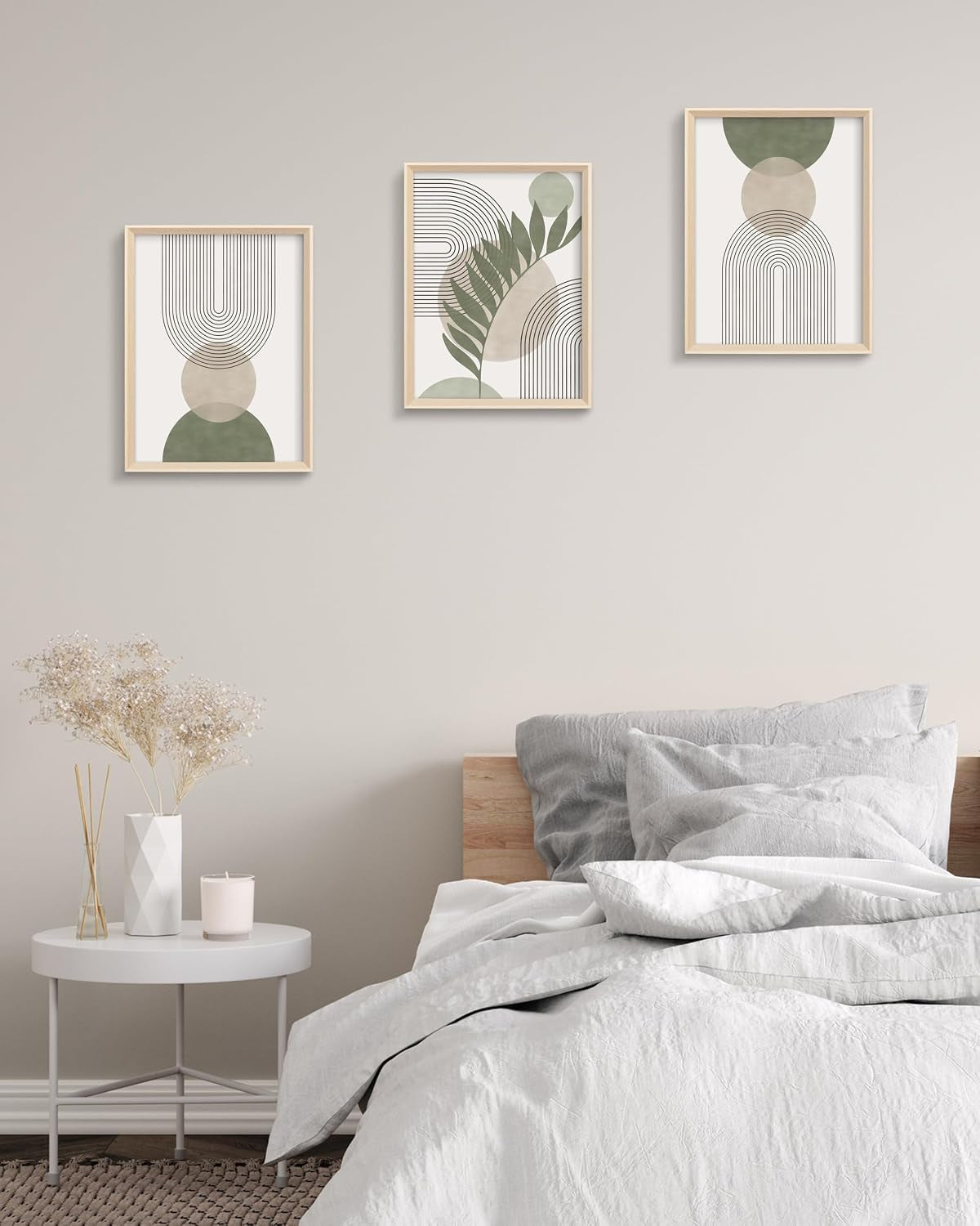 Three framed abstract prints in sage and neutral tones hung above a bed in a minimalist bedroom