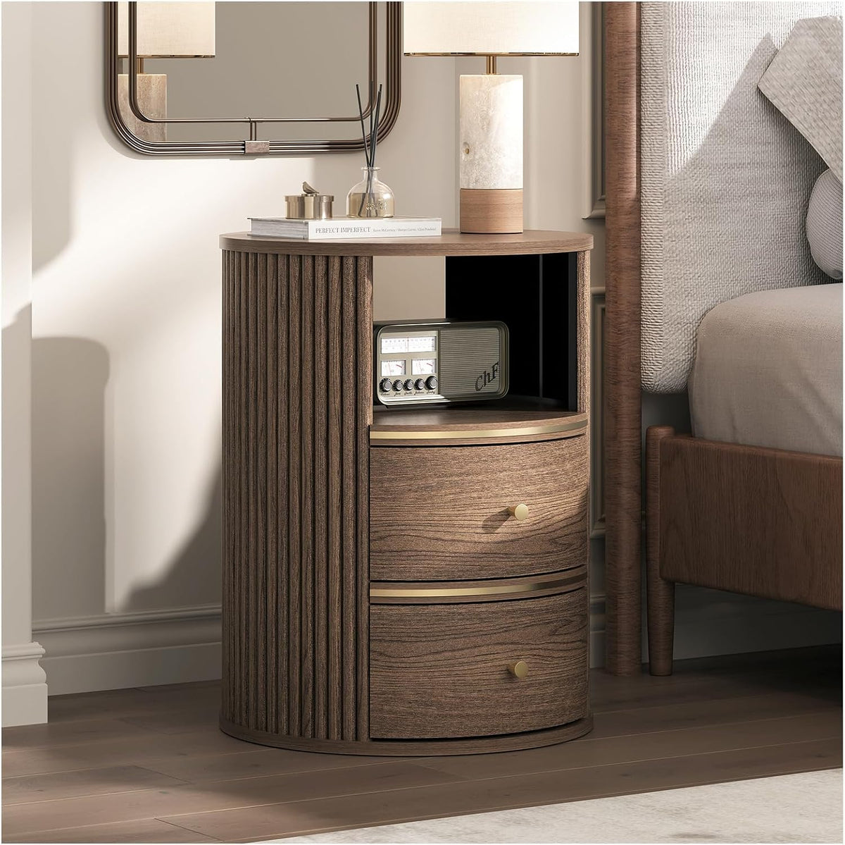 Round walnut-finish fluted nightstand with open shelf and two drawers, angled bedside view with lamp on top