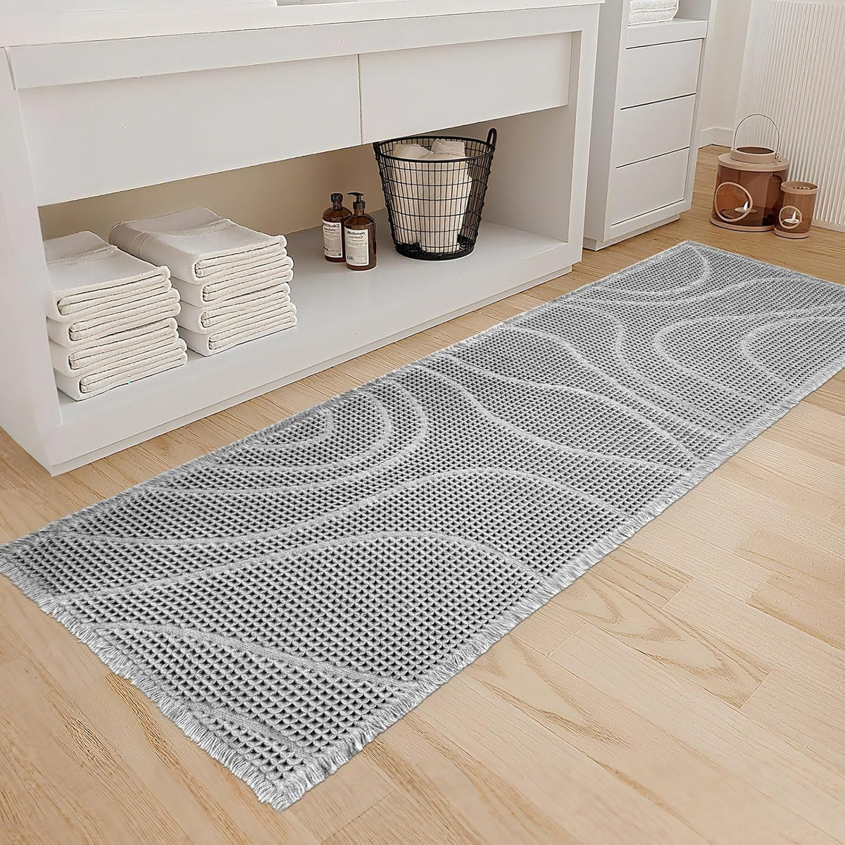 Light gray runner with wavy raised pattern laid in front of a white vanity and open shelf.