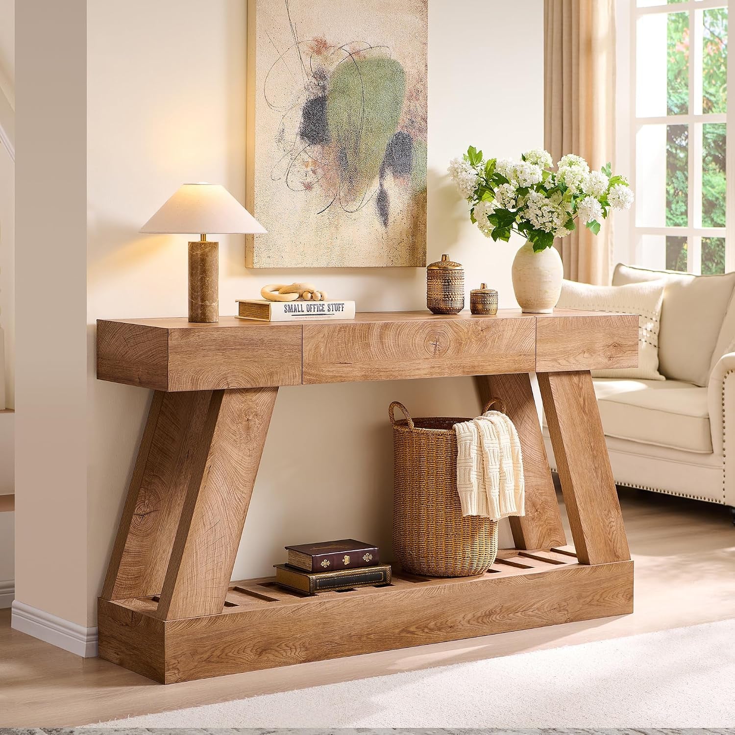 Angled room view of the light brown console table beside a sofa, with decor and a basket.